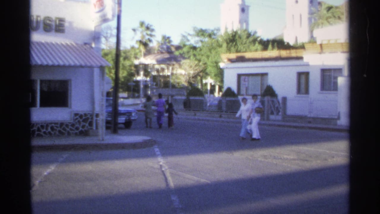 Pedestrians near a street corner with a steak house sign and white buildings.
