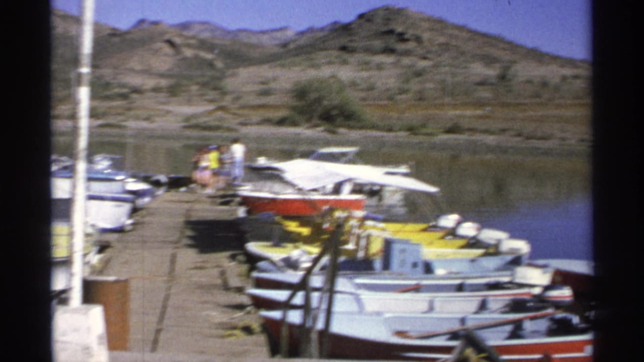 Guaymas marina boats sit along a dock in 1975 home-movie footage, with calm water and arid hills in the background.