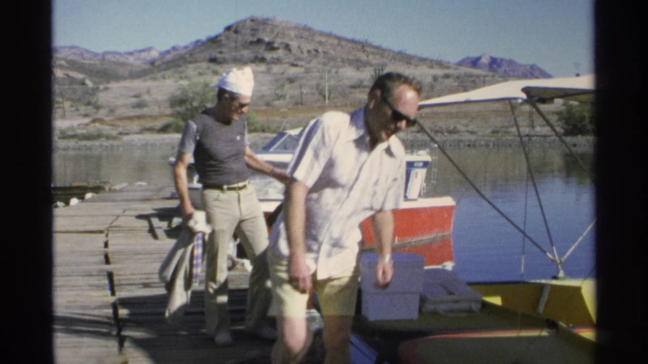 Two adult men stand near a docked motorboat while handling gear.