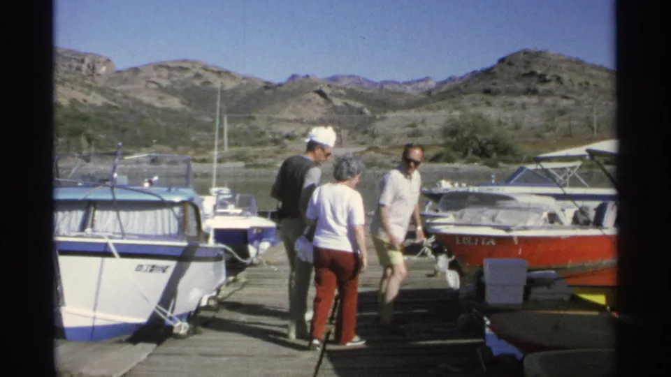 The group stands on a Guaymas dock in 1975 as the older woman with a cane approaches a red-and-white passenger boat.