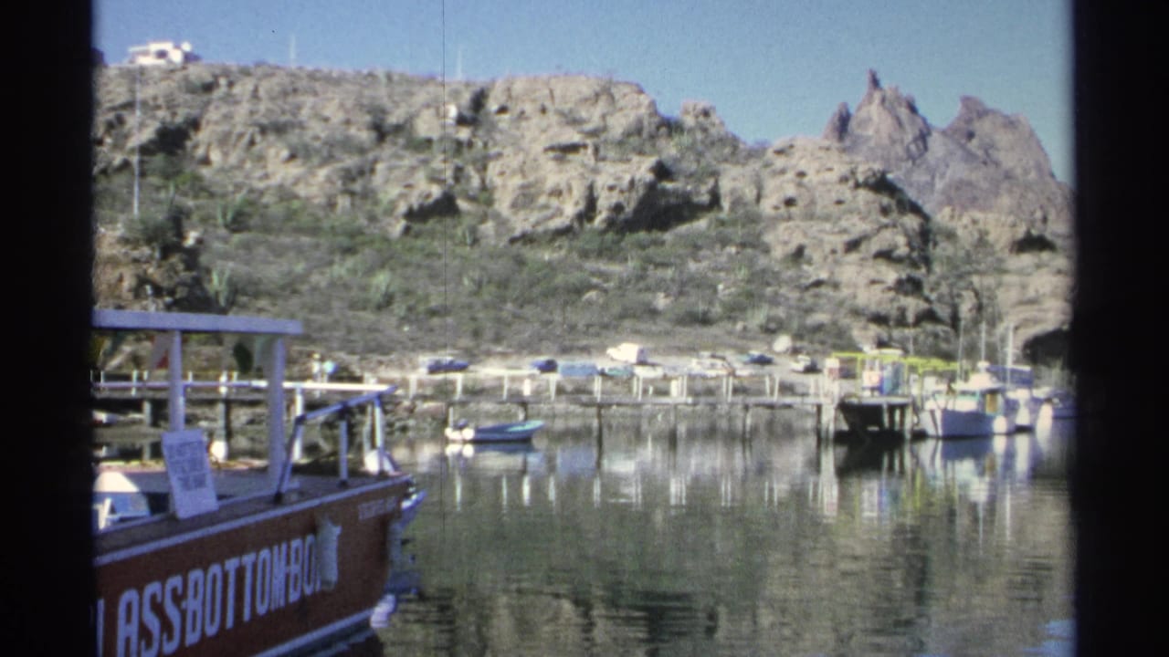 Marina water, docks, small boats, and rocky hills with a boat edge at left.