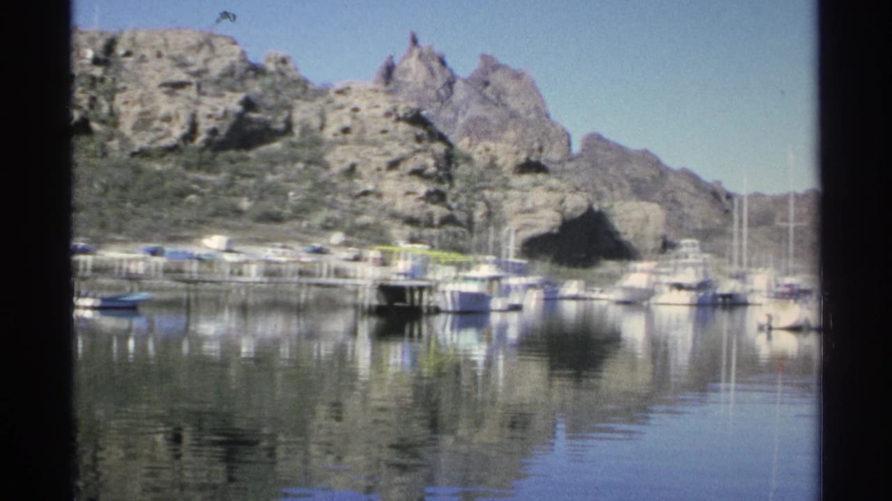 Boats moored in calm water below rocky desert hills.