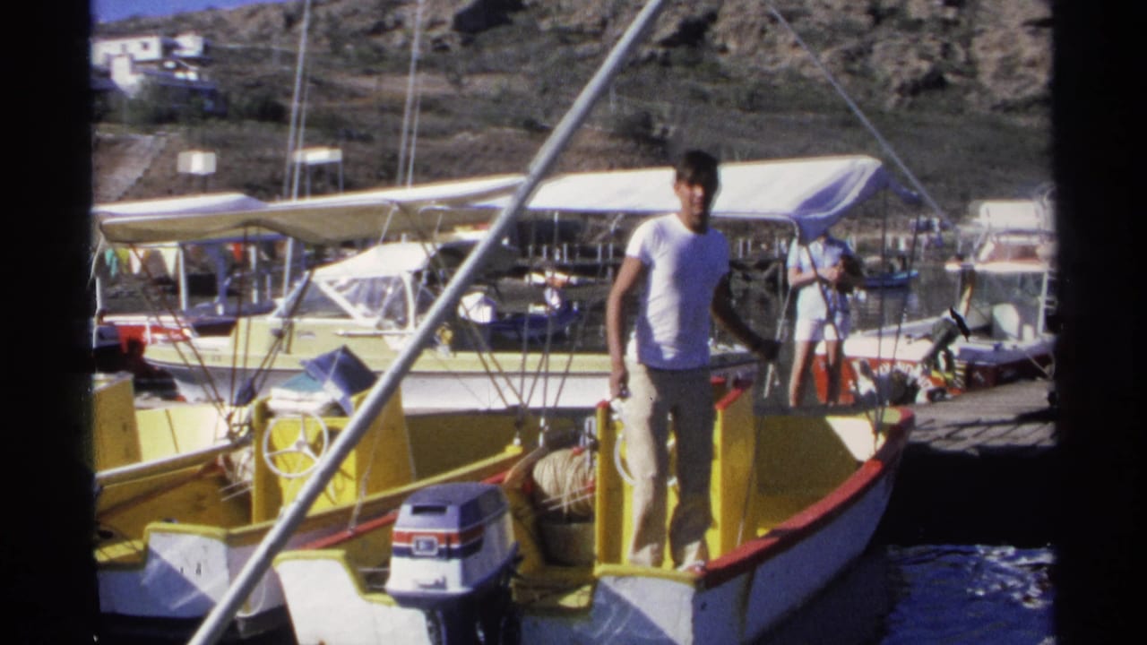 Young man standing on a yellow motorboat beside a marina dock.