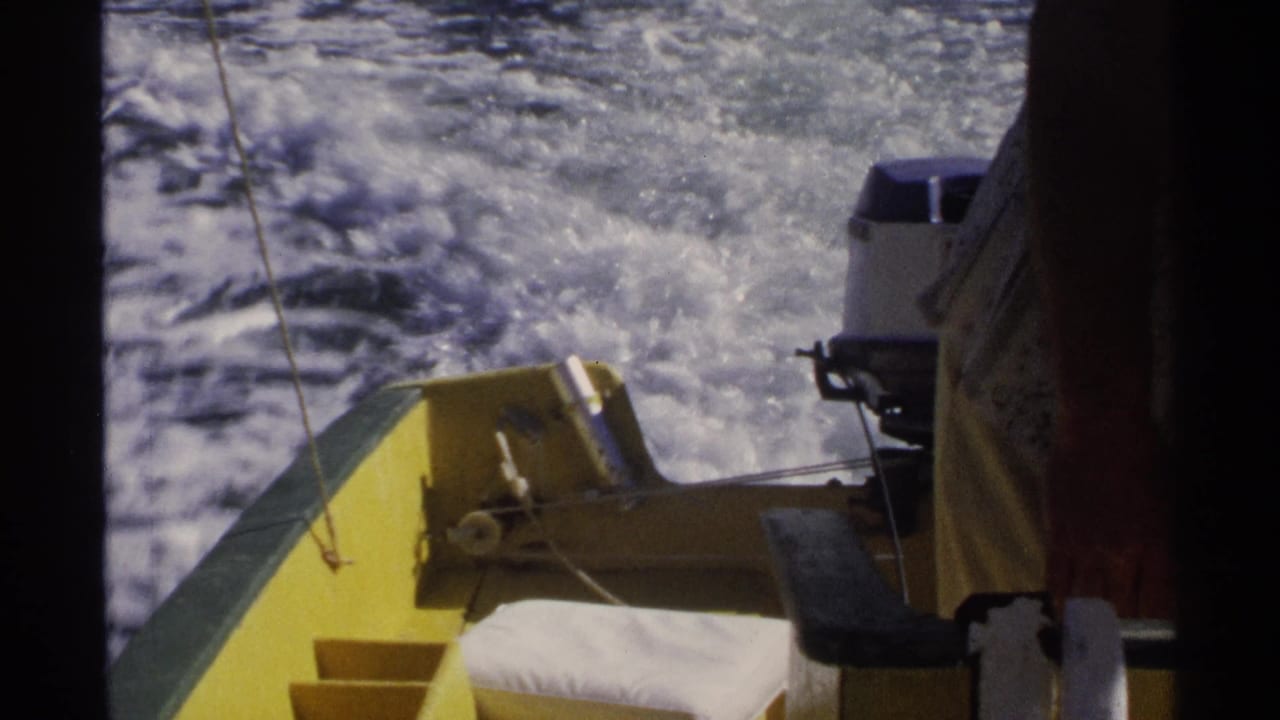 Yellow motorboat stern and outboard motor seen from aboard as wake trails over blue water.