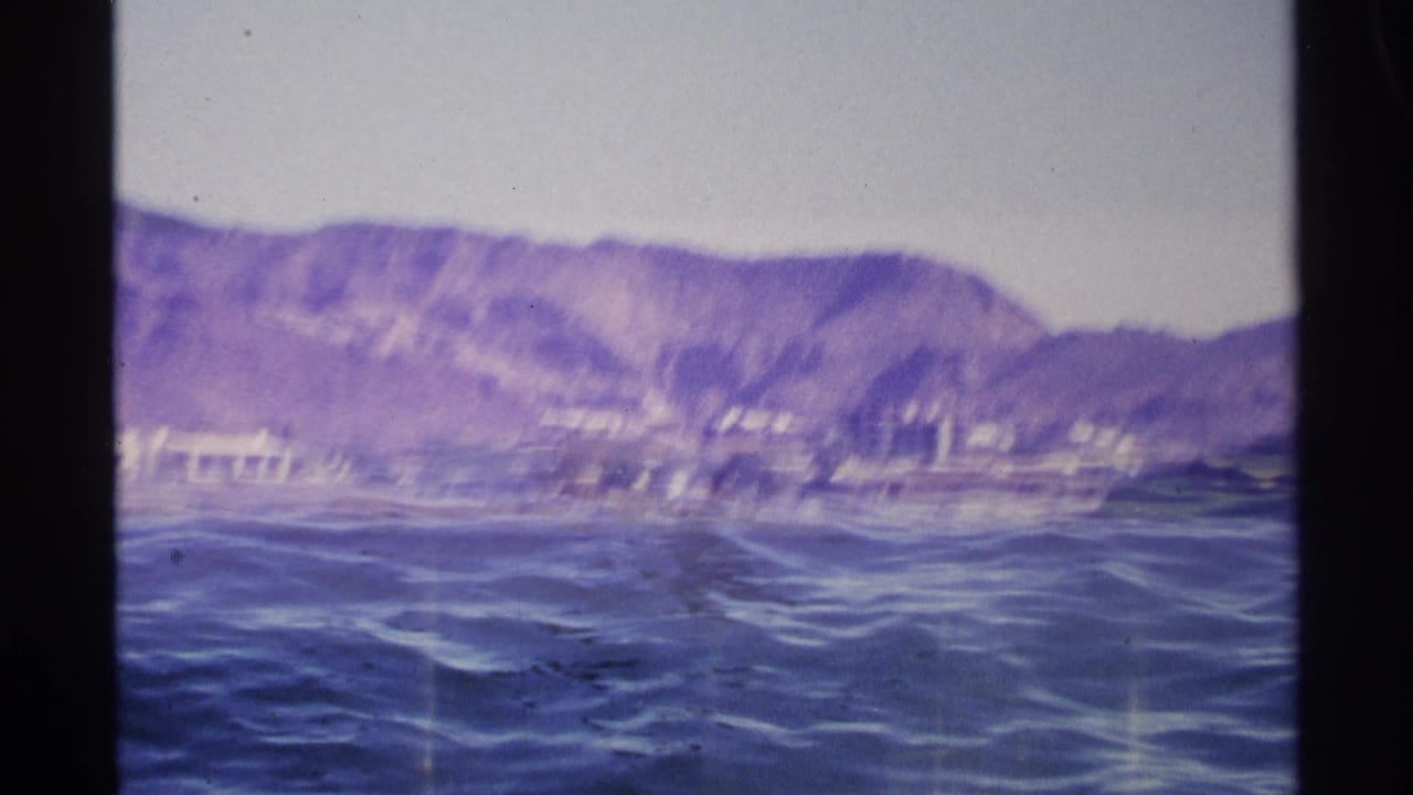 Coastal water with mountains and shoreline buildings seen through 8mm frame edges.