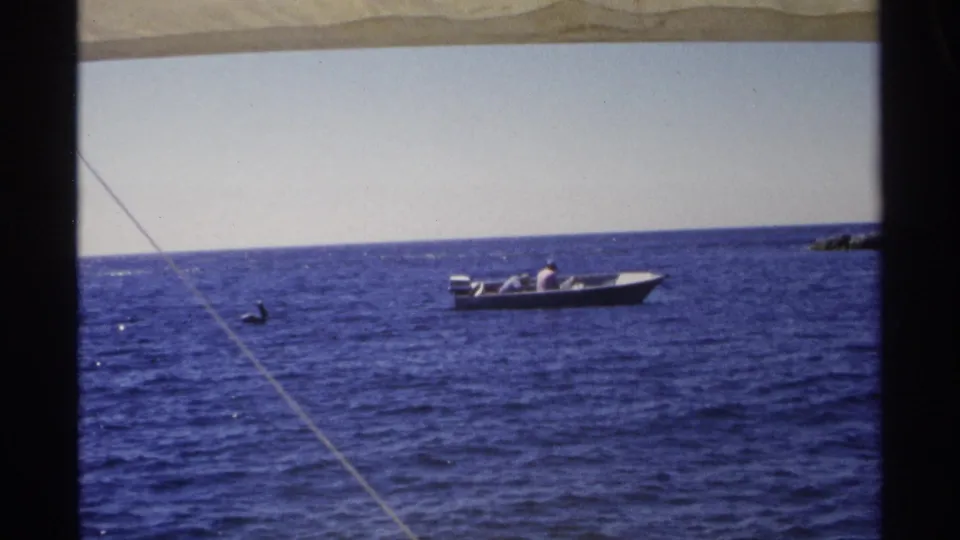 Small motorboat with distant occupants crosses blue water near Guaymas, Mexico, in 1975 home-movie footage.