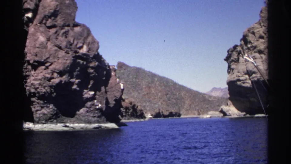 1975 Guaymas, Mexico boat-view frame with rugged cliffs, distant hills, and calm blue sea water.