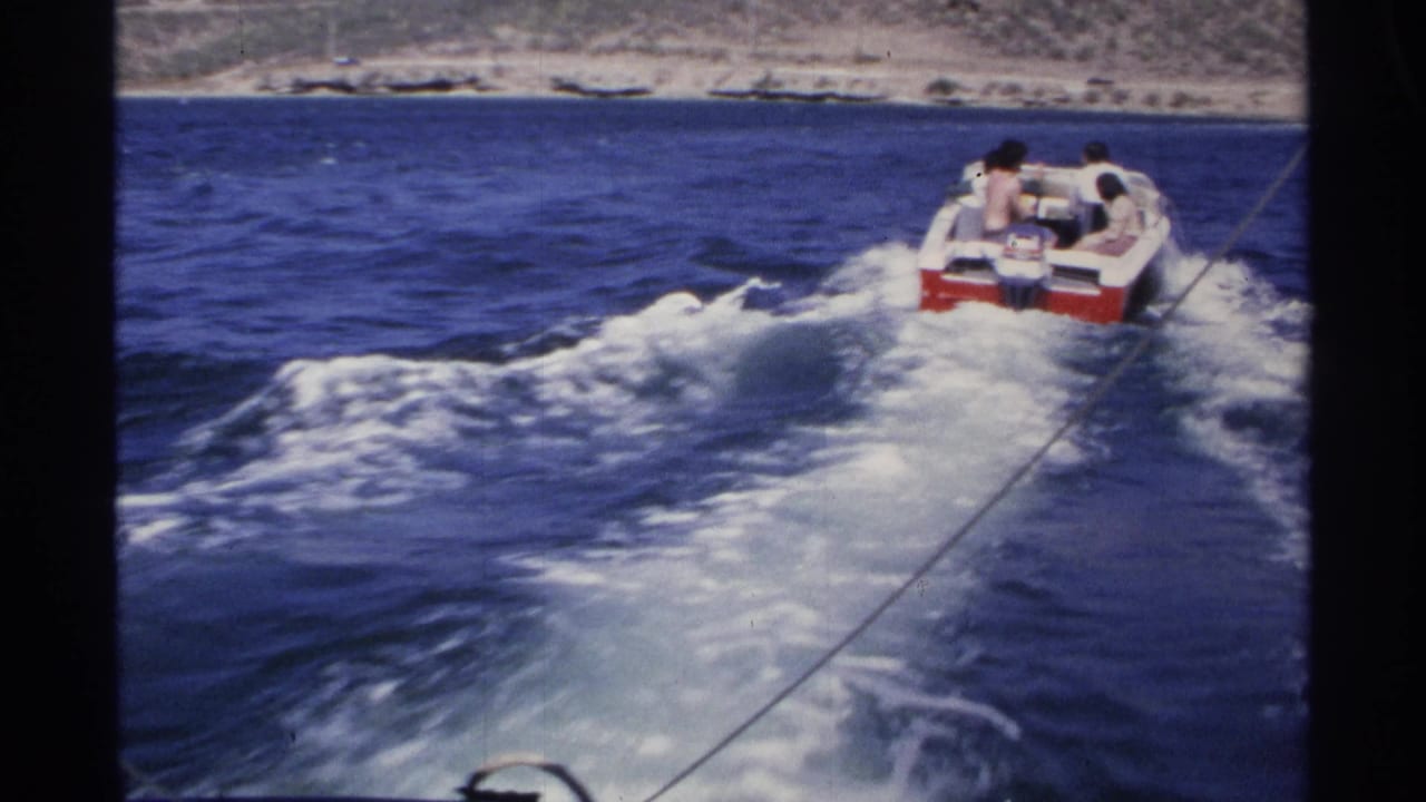 Red-and-white speedboat ahead of the camera boat leaving a foamy wake.