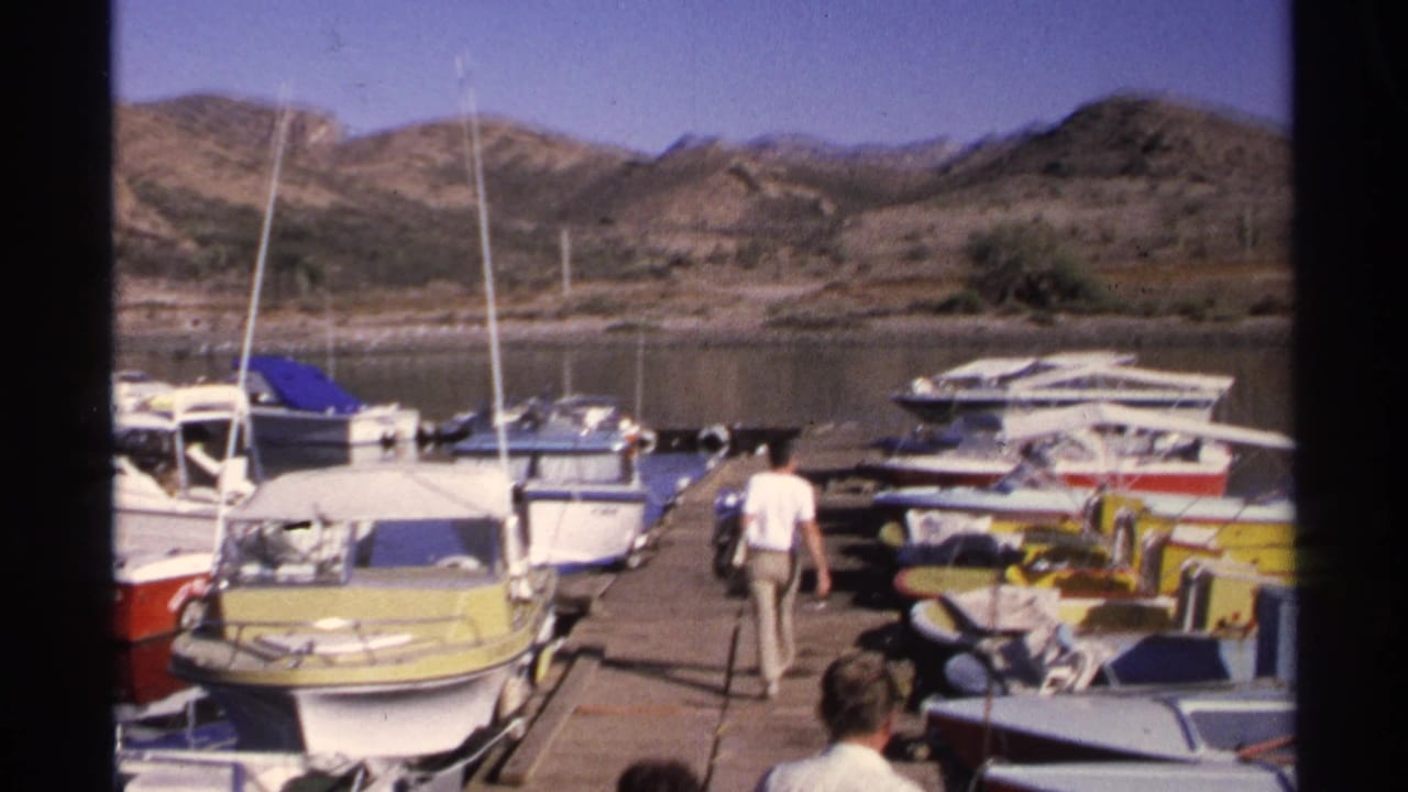 Man walking away on a dock between moored boats at a marina.