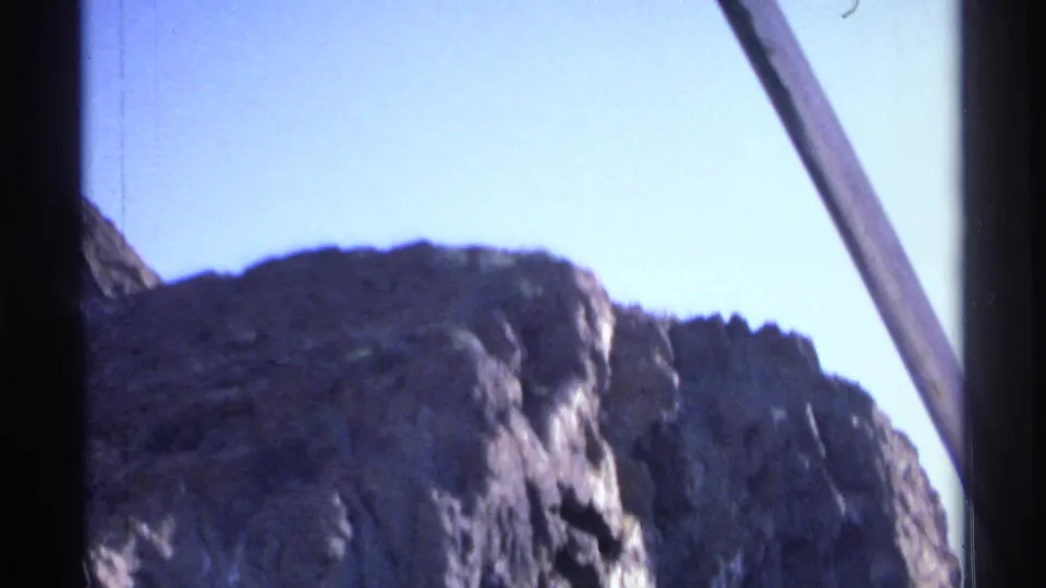 1975 Guaymas shoreline view looking up toward rugged rock and blue sky from a moving boat.