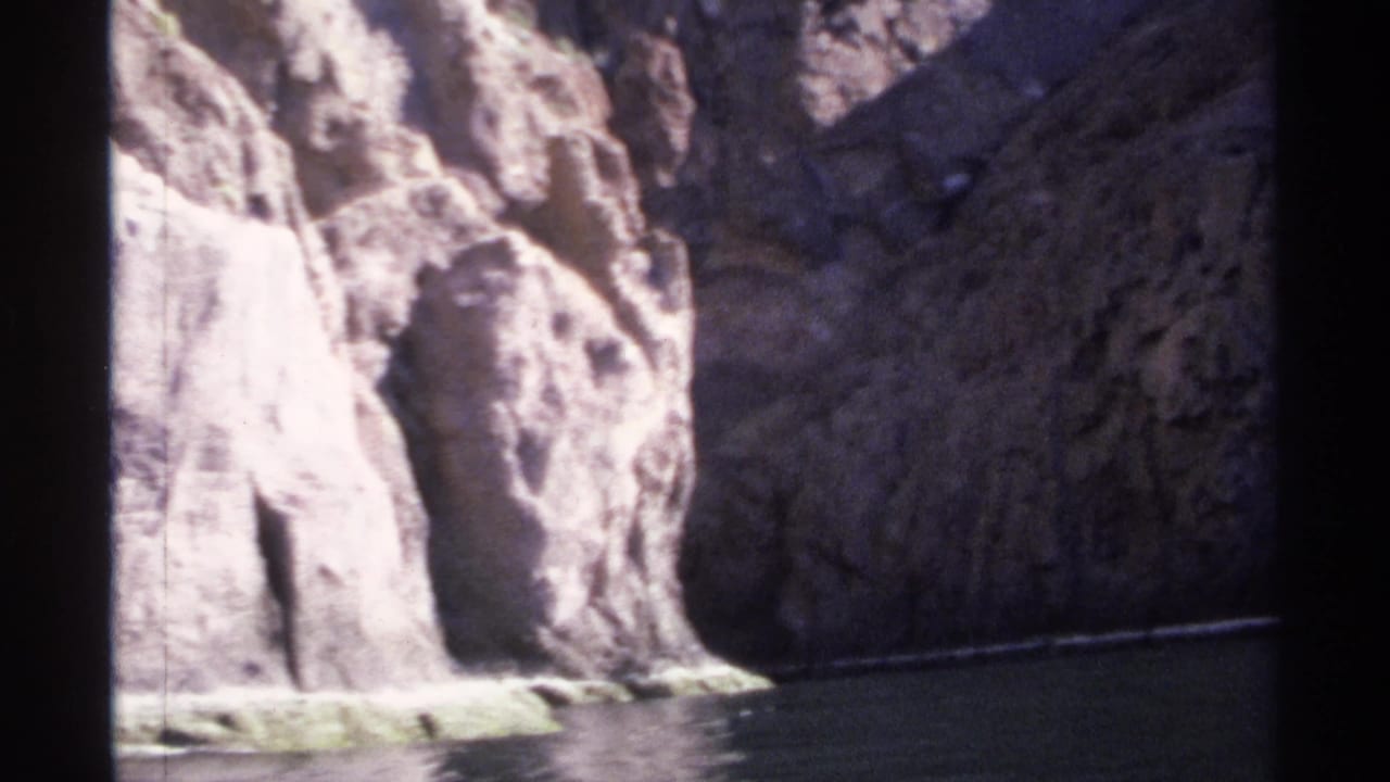Narrow river bend bordered by tall, shadowed canyon cliffs.