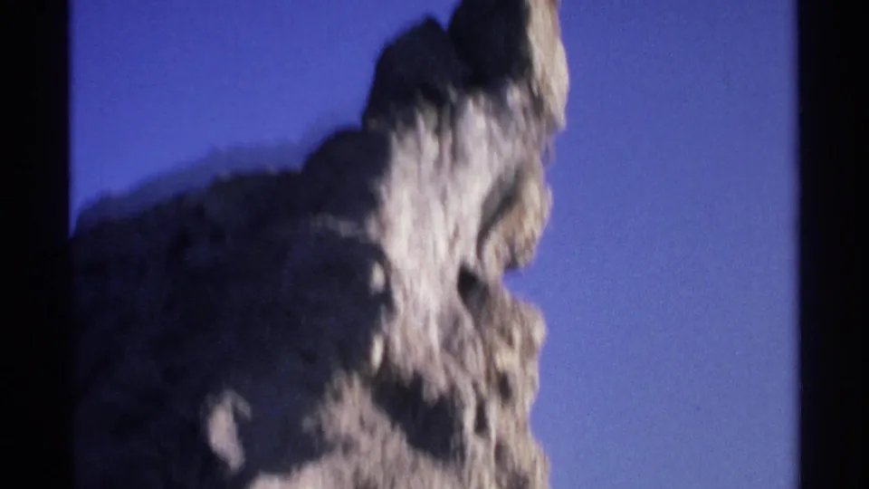 1975 Guaymas home-movie frame showing a soft, handheld view of a jagged rock point and shadowed stone surface.