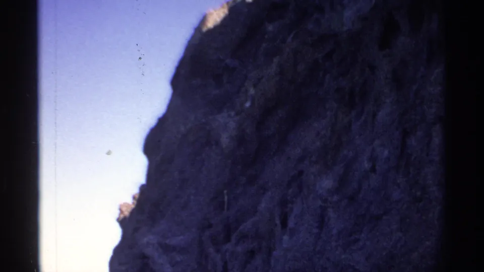 Rocky coastal cliff and calm water in Guaymas, Mexico, captured on 1970s 8mm home-movie film.
