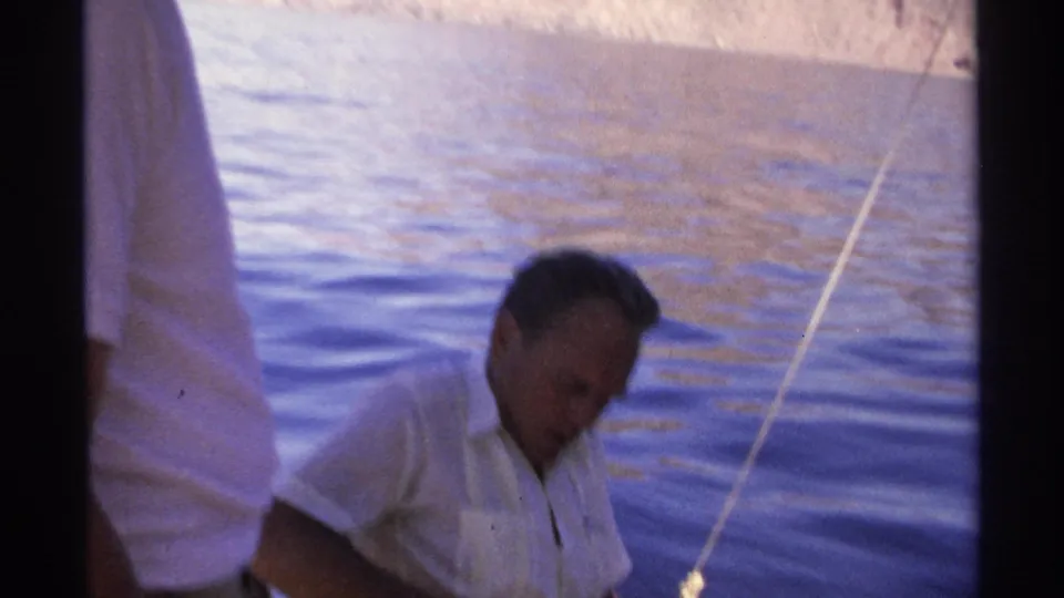 Soft 8mm frame from Guaymas in 1975 showing a man seated in a small boat as another figure stands partly in front of the camera.