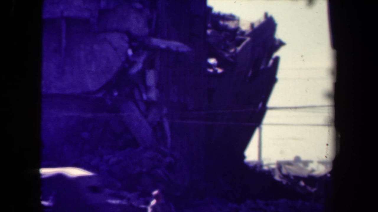 Damaged wooden structure and rubble seen through dark 8mm frame edges.