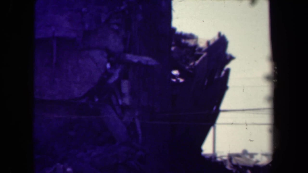Broken structure with splintered upper section beside a bright sky.
