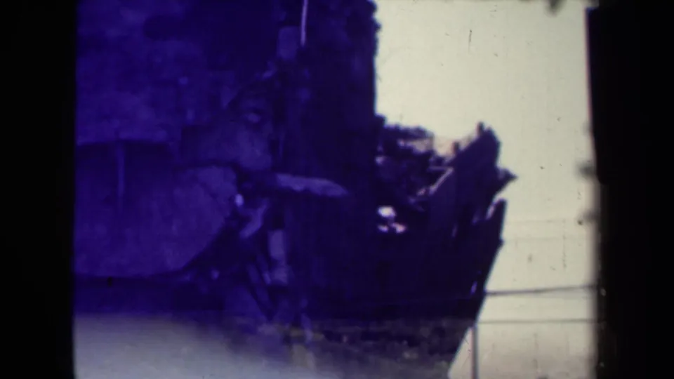 1944 Manila frame showing damaged wood, rubble, bright sky, utility lines, and visible 8mm gate edges.