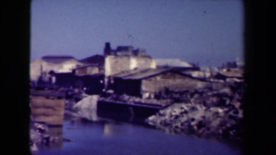 1944 Manila footage showing ruined waterfront buildings, debris, and a canal or water edge under a pale sky.