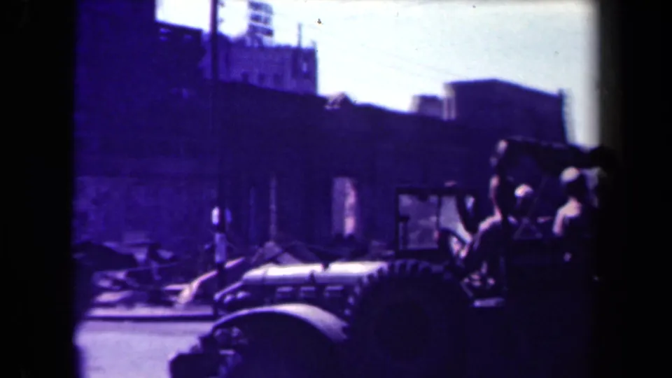1944 Manila footage showing a military-style jeep with visible passengers moving past damaged buildings and rubble.