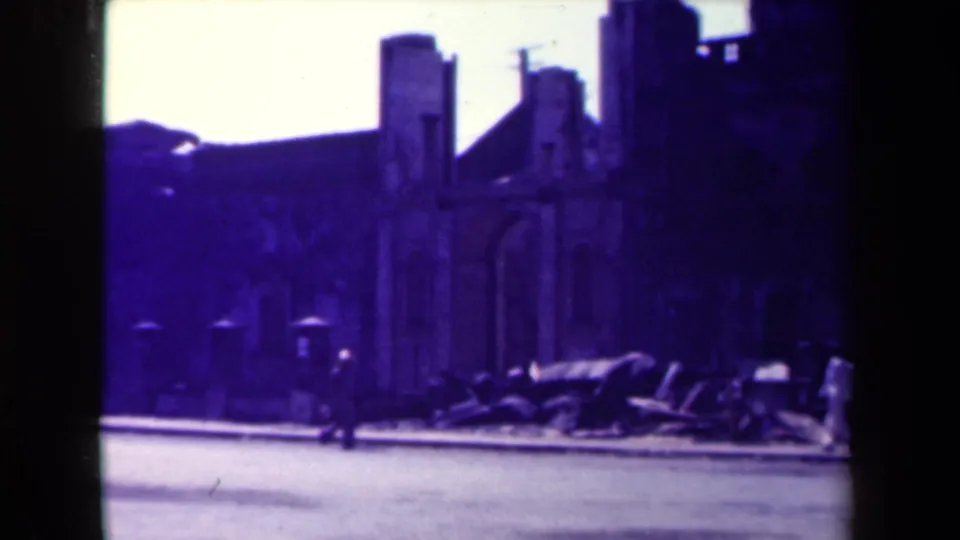 1944 Manila street view showing a damaged masonry facade, rubble along the curb, and pedestrians moving through the scene.