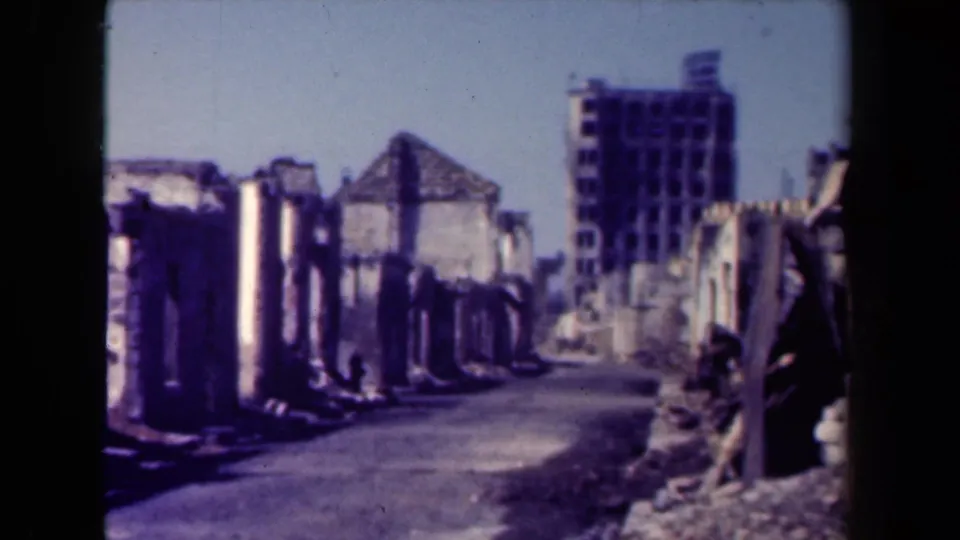 1944 Manila street framed by burned or collapsed building walls, scattered debris, and a taller structure at the far end.