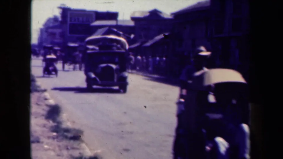 A Manila street scene shows a large mid-century vehicle, pedestrians, and storefronts fading into the distance.