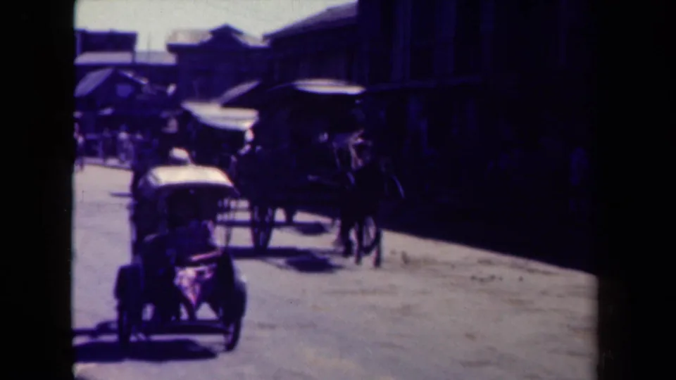 A horse-drawn carriage, small vehicle, and pedestrians move through a Manila street framed by dark storefront shadows.