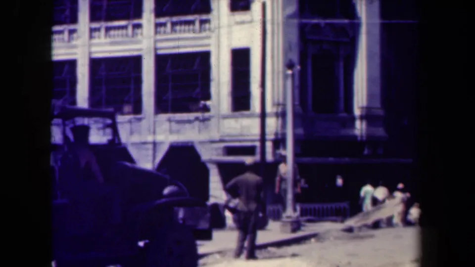 Manila street scene from the 1940s showing a man walking past older cars with pedestrians near colonial-style building facades.