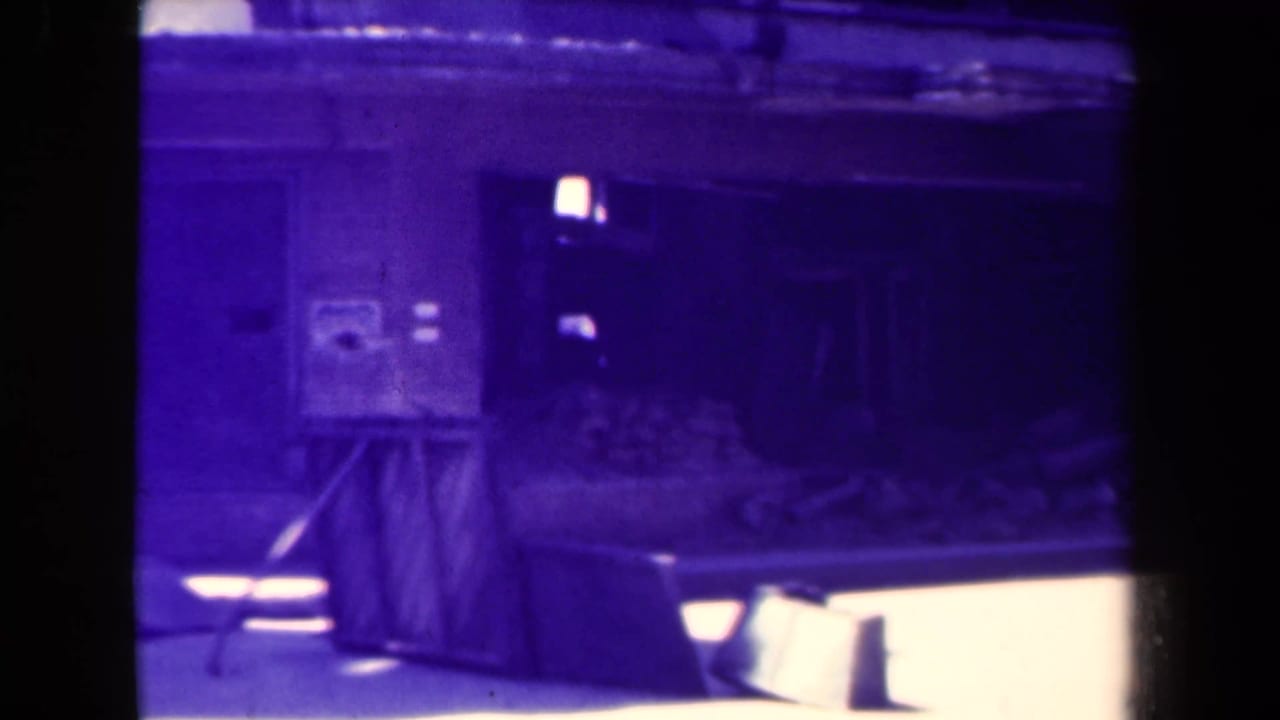 Dark purple-tinted view of a damaged structure with rubble and a crate-like object in the foreground.