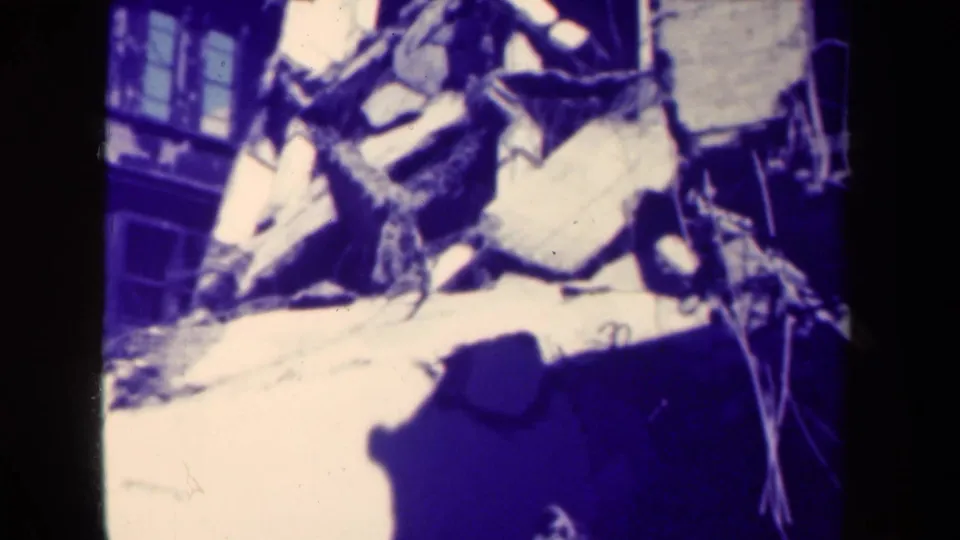 1944 Manila aftermath frame showing broken structural debris, nearby windows, and strong shadow on aged 8mm film.