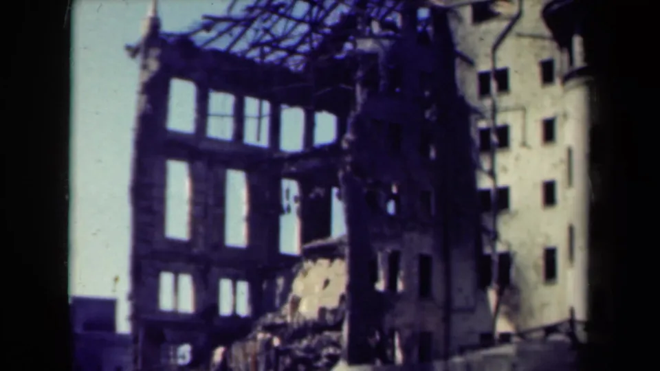 1944 Manila frame showing the upper portion of a wrecked multi-story building with roof beams exposed against a pale sky.