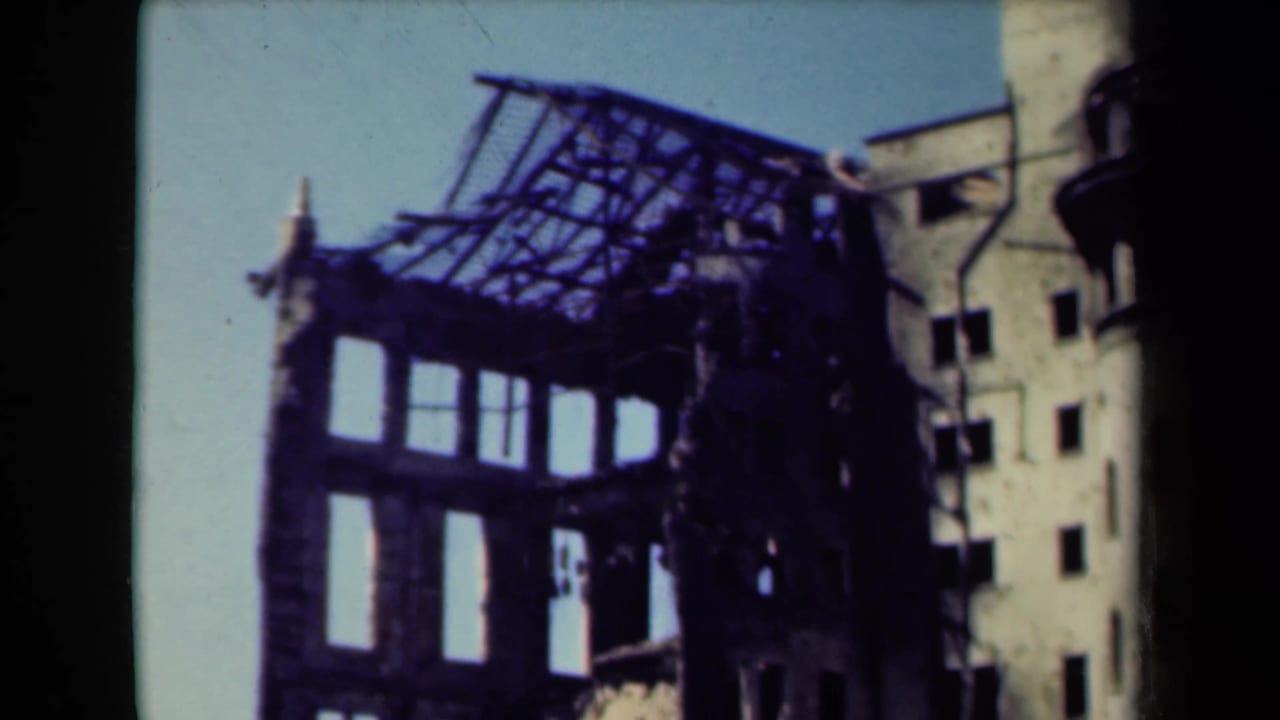 Damaged multi-story building shell with exposed roof framing and open window bays.
