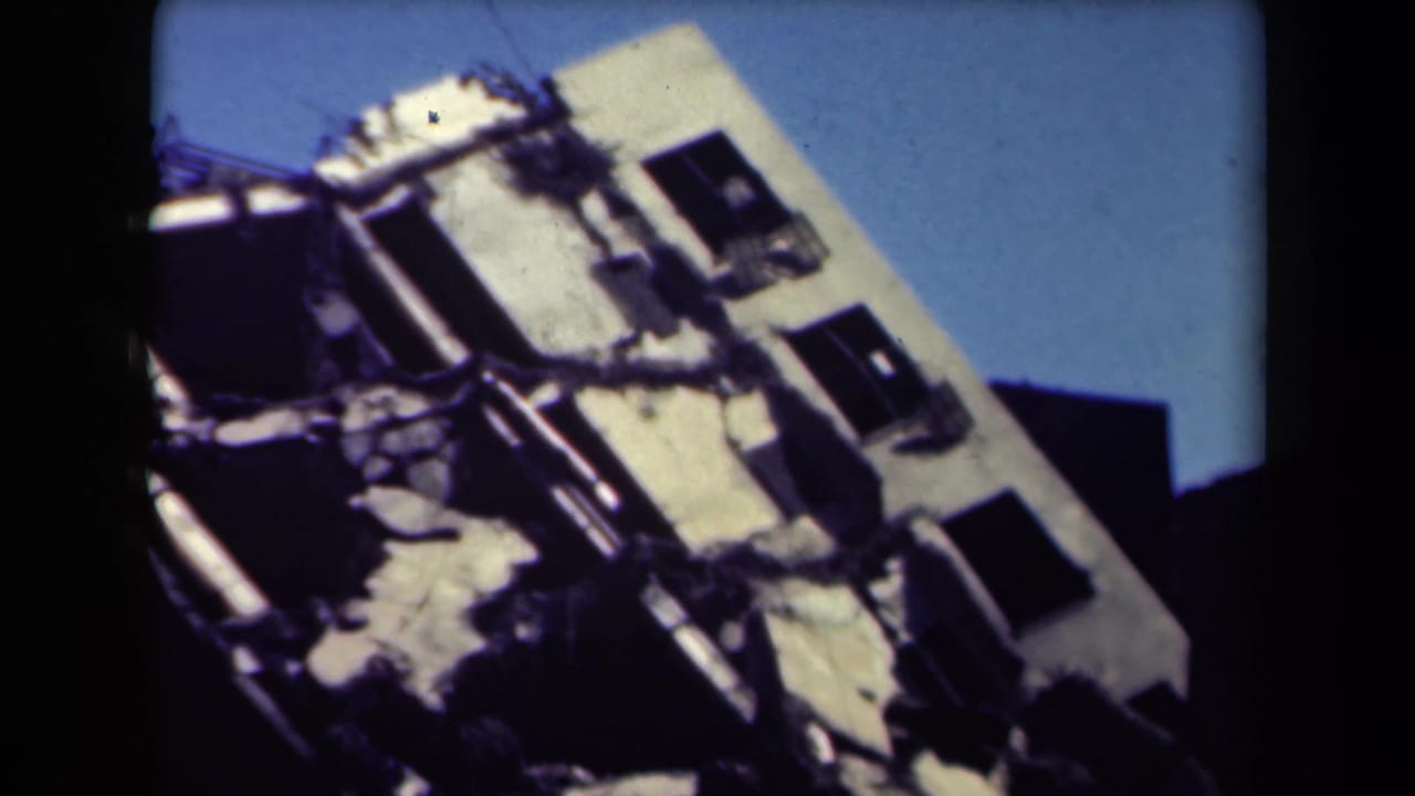 Similar view of a damaged building facade with broken structure and dark openings.