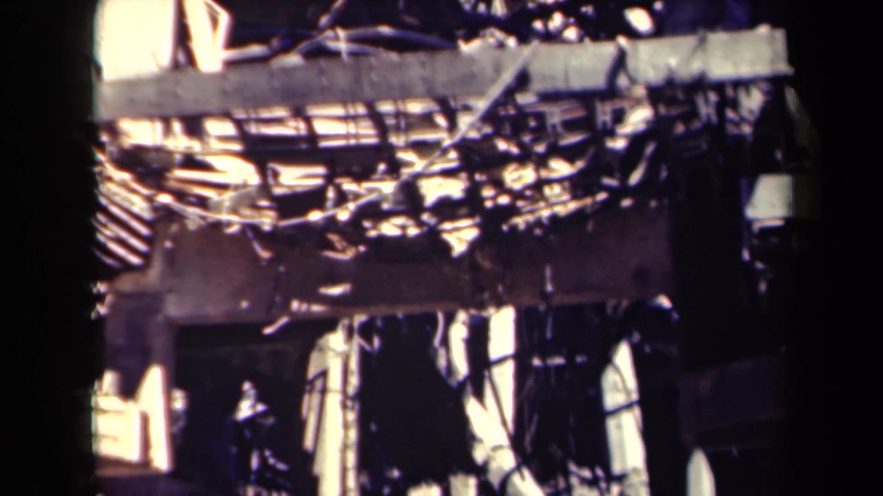 1944 Manila 8mm frame of severe structural damage, with exposed framing, debris, and bright fractured wall surfaces.