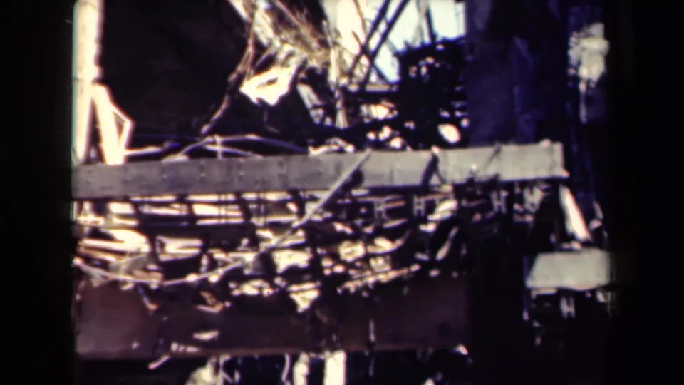 1944 Manila 8mm frame of ruined building damage, including twisted metalwork, fractured concrete, and dark openings.