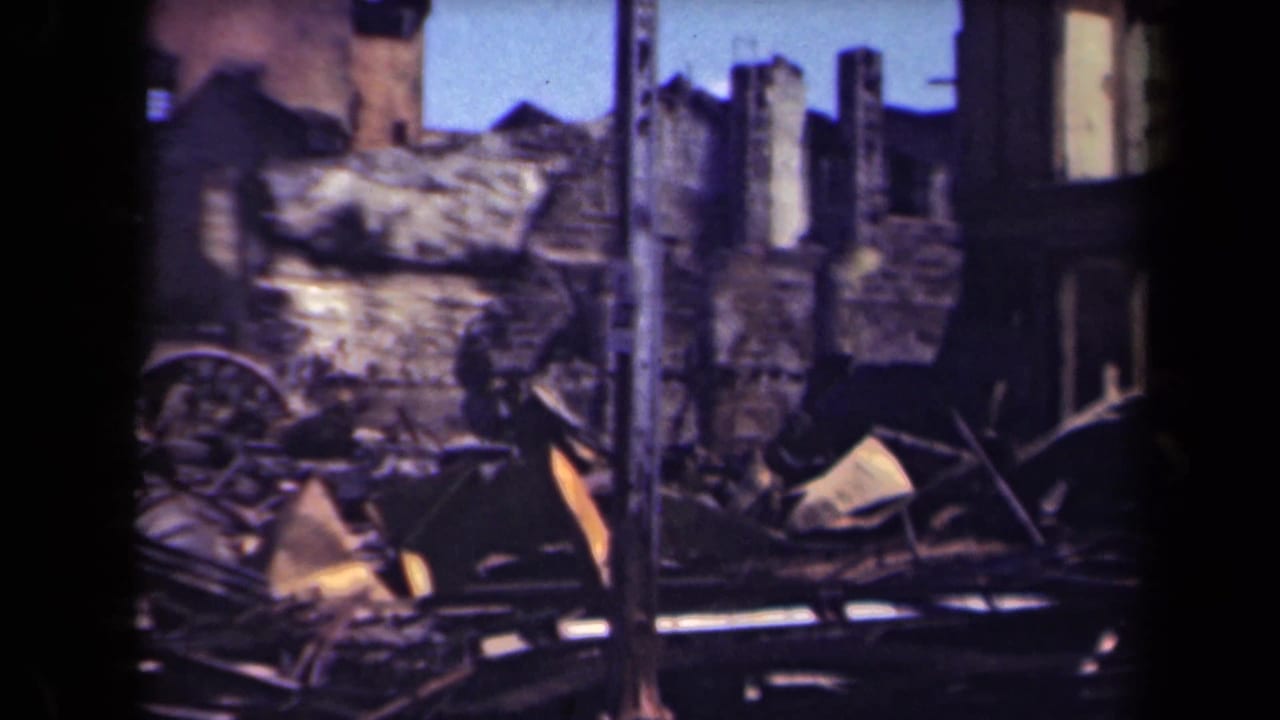 Ruined wall, scattered debris, and a wagon wheel among burned building remains.