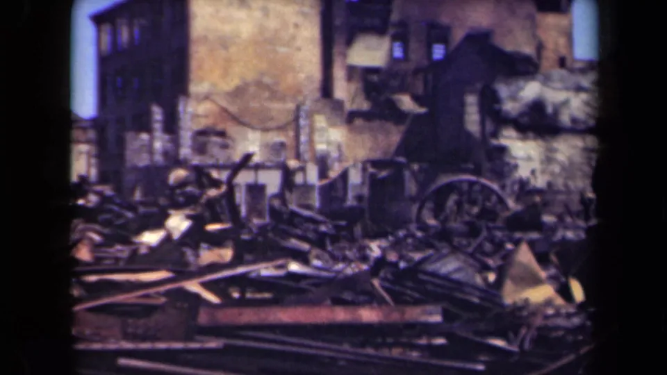 1944 Manila home-movie frame showing debris-strewn ruins, damaged wall surfaces, and a wagon wheel near collapsed material.