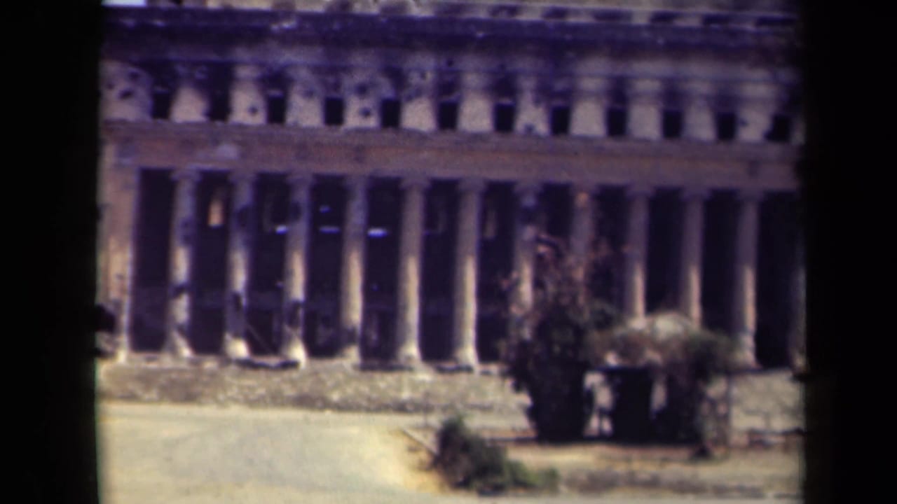 1944 Manila frame of a large stone or concrete facade with tall columns, visible pockmarks, and low vegetation at street level.