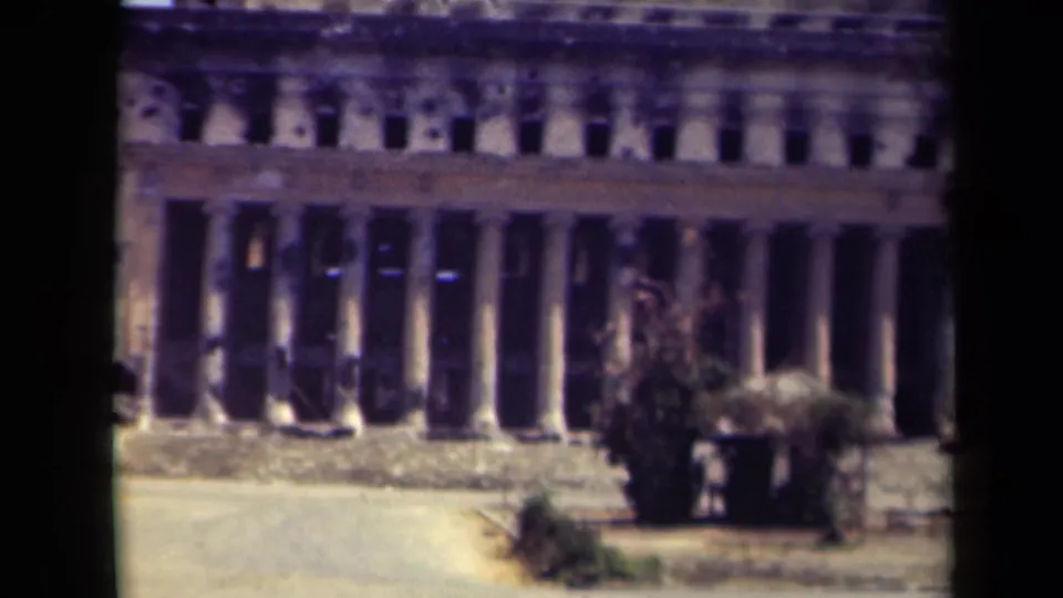 1944 Manila frame of a large stone or concrete facade with tall columns, visible pockmarks, and low vegetation at street level.
