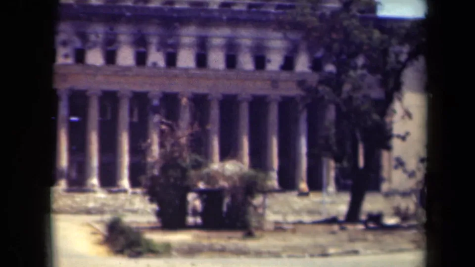 1944 Manila frame showing the same damaged columned building, with tree cover at the right edge and strong 8mm frame borders.