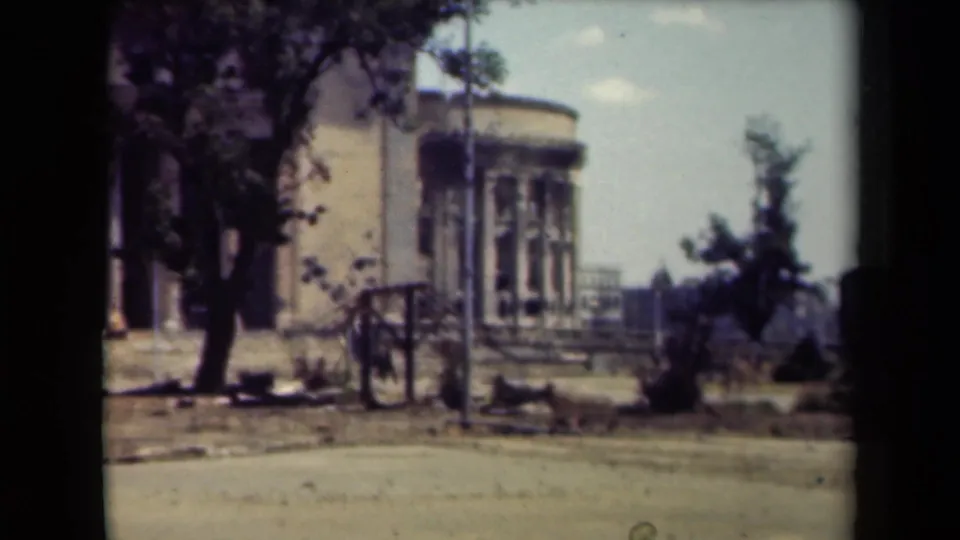 The final frame holds on the rounded exterior section, nearby trees, railings, and open street area in 1940s Manila footage.
