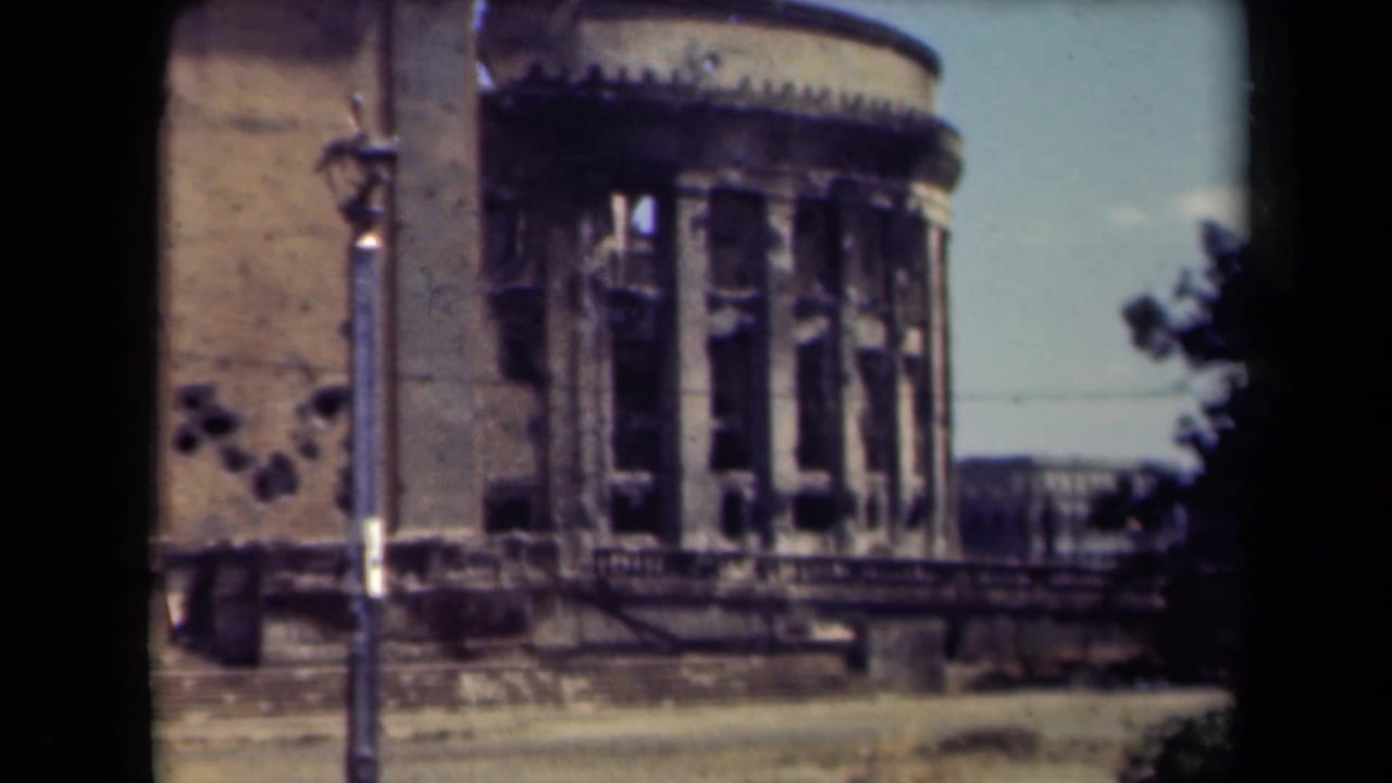 Closer view of a rounded damaged facade with broken windows and wall marks.