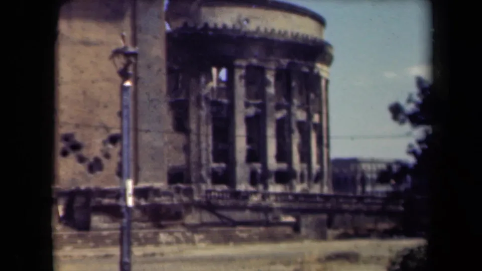 1944 Manila frame showing a closer view of a rounded stone facade with shattered window openings, pitted wall marks, steps, and a lamppost.