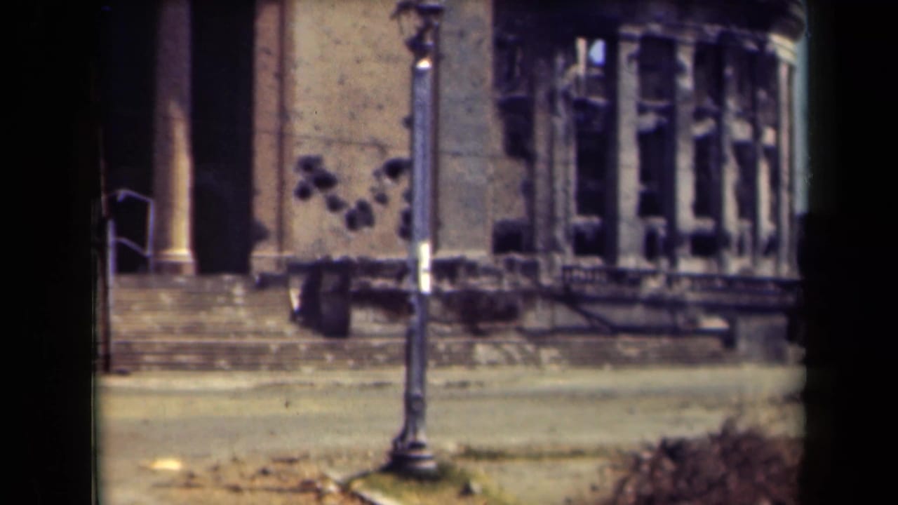1944 Manila street view of a damaged stone building near the old walled city, with broken window openings and a lamppost in the foreground.