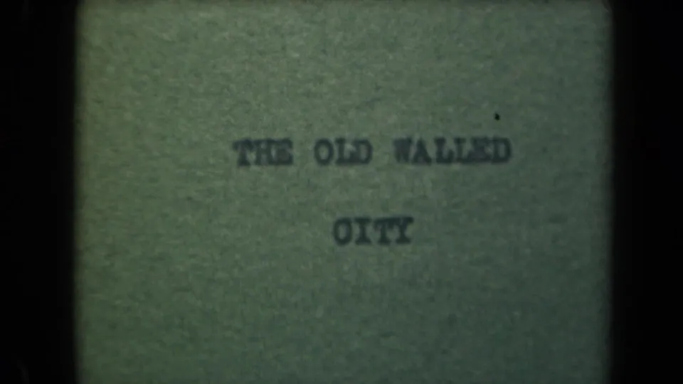 Repeated 8mm title-card frame for THE OLD WALLED CITY, with green paper tone, soft type, and black film edges.