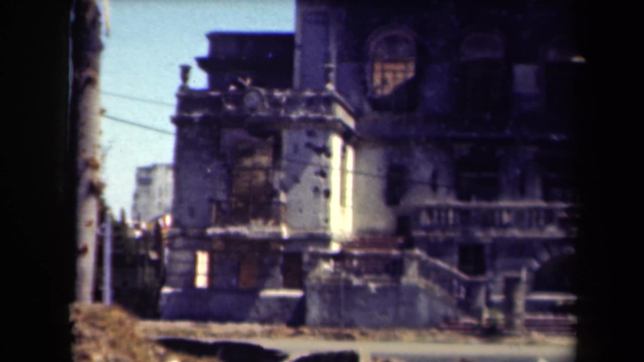 War-damaged building facade with pocked walls and balcony details.