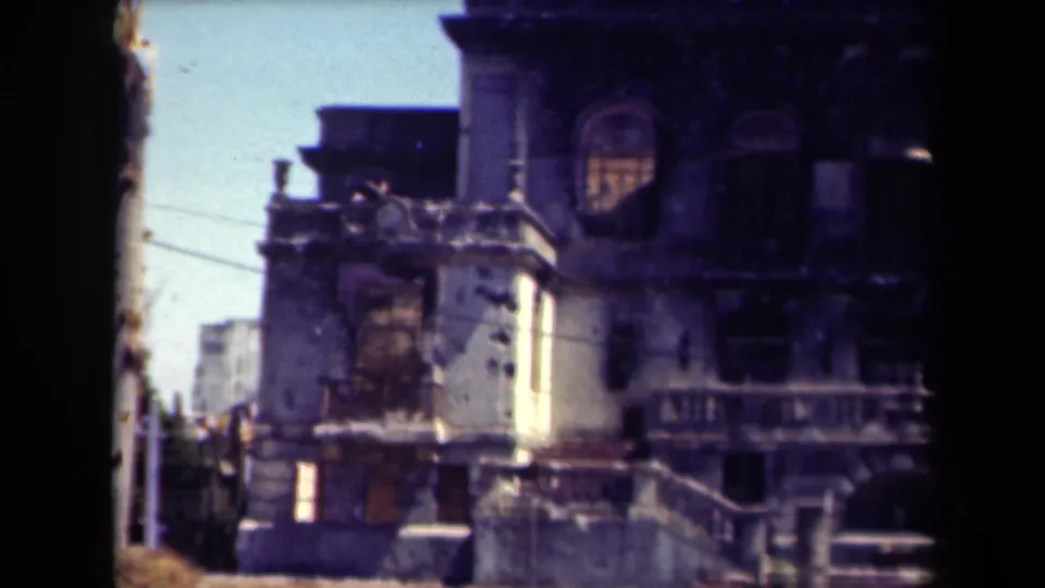 1944 Manila 8mm view of the same war-damaged building, with exterior stairs, dark window openings, and soft faded color.