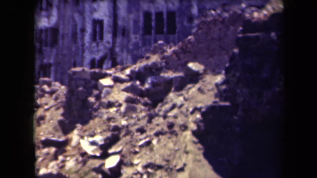 Damaged building wall and rubble slope with dark vertical film edge.