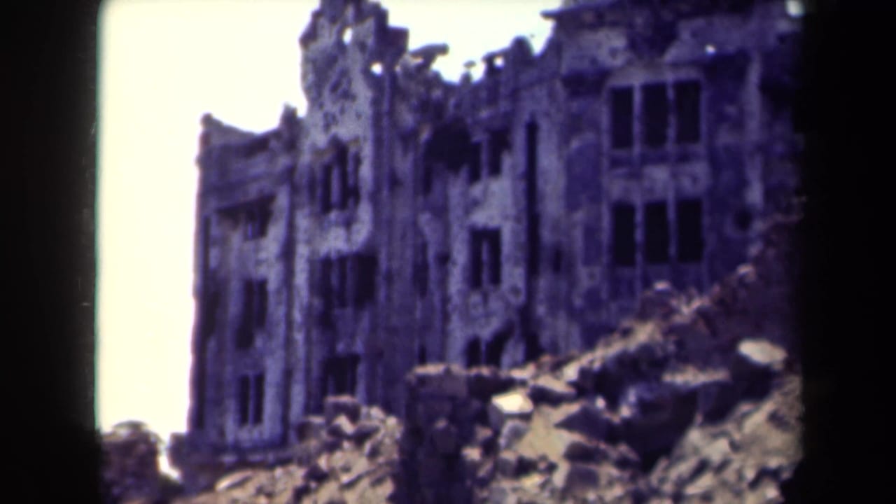 Damaged multi-story building facade behind rubble piles.