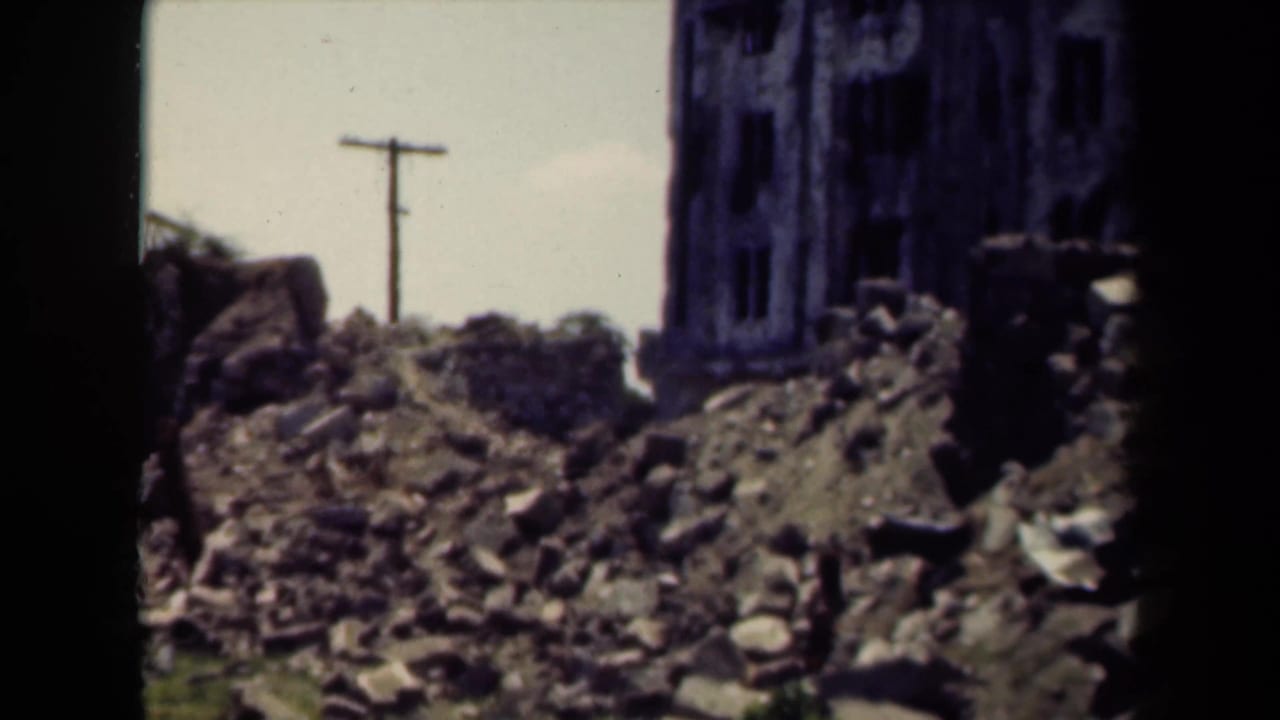 Rubble piles and partial ruined building walls with a utility pole behind them.
